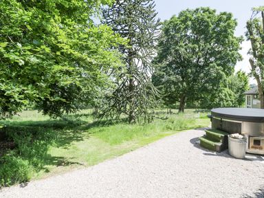 An outdoor area with a round hot tub gravel path trees and green grass at Pentre Hall Bronygarth near Chirk