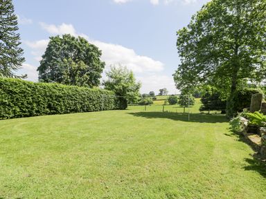 A grassy garden area with a badminton net and trees in the background at Pentre Hall in Bronygarth near Chirk