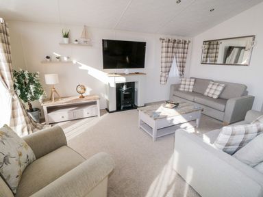 A living room with sofas a coffee table a television and a lamp at Rockpool Retreat in Runswick Bay near Hinderwell