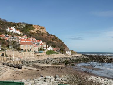 A coastal village with houses on a hillside near rocky shore and sea at Rockpool Retreat in Runswick Bay near Hinderwell