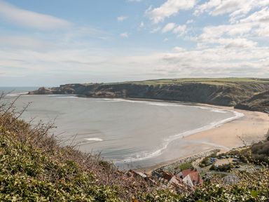 A bay with a sandy beach surrounded by cliffs and houses at Rockpool Retreat in Runswick Bay near Hinderwell