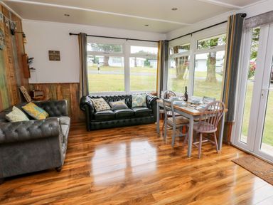 A sitting area with two sofas and a dining table with chairs next to large windows at Ty Haf in Roch
