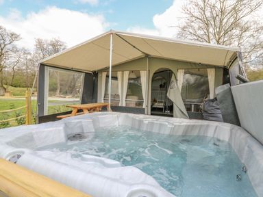 A hot tub outside a tent with a picnic table in a grassy area at The Salmon in Nantmel near Rhayader