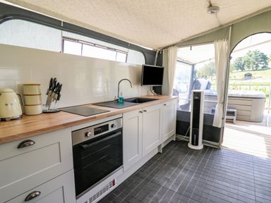 A kitchen with countertops stove sink oven and knife set next to a window and door to an outdoor area at The Salmon in Nantmel near Rhayader
