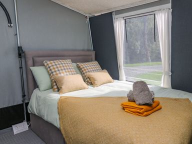 A bedroom with a made bed with folded towels on top near a window at The Salmon in Nantmel near Rhayader
