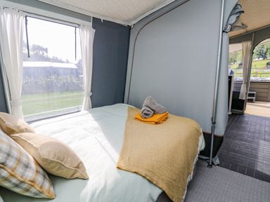A bedroom with a bed and pillows next to a window with curtains at The Salmon in Nantmel near Rhayader