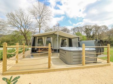 A wooden deck with a hot tub and picnic table in front of a tent at The Salmon in Nantmel near Rhayader