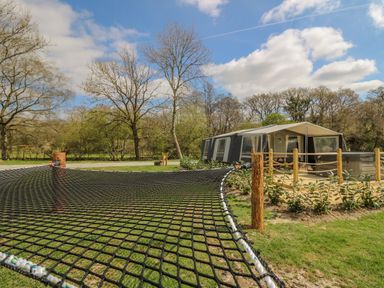 A large outdoor netted trampoline next to a tent with a wooden deck and hot tub at The Salmon in Nantmel near Rhayader
