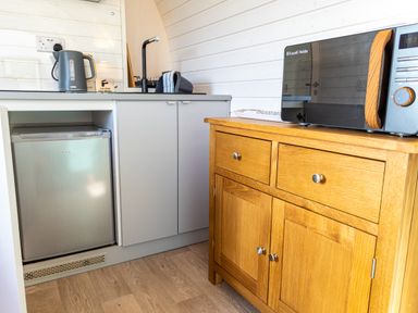 A kitchenette with a small fridge kettle sink microwave and wooden cabinet at Veiko - Mayflower Meadow Burshill near Brandesburton