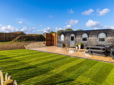 A garden with a grass lawn patio chairs a small building and a hot tub at Veiko - Mayflower Meadow in Burshill near Brandesburton