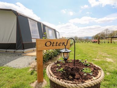 A garden bed with a lantern and a wooden sign that says Otter near a tent structure at The Otter in Nantmel near Rhayader