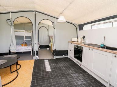 A kitchen area with white cabinets and appliances next to two rooms with bunk beds and a double bed at The Otter in Nantmel near Rhayader