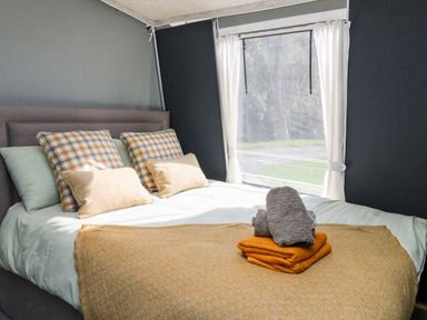 A bedroom with a bed made with pillows blankets and towels near a window at The Otter in Nantmel near Rhayader