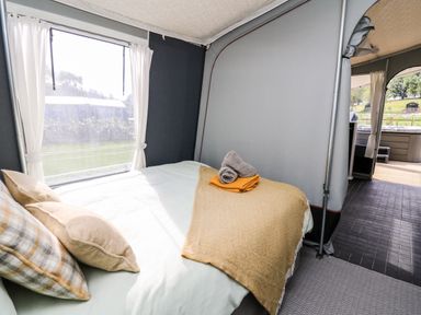 A bed with pillows and folded towels near a window in a tent at The Otter in Nantmel near Rhayader
