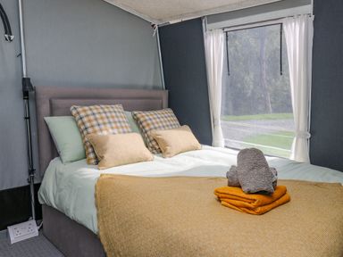 A bedroom with a bed with pillows and folded towels near a window at The Heron in Nantmel near Rhayader