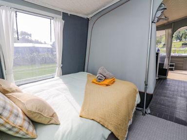 A bedroom with a bed and folded towels inside a tent at The Heron in Nantmel near Rhayader
