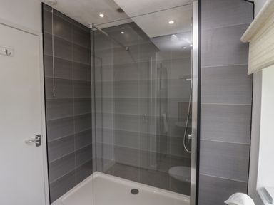 A shower area with gray tiled walls and a glass partition at 9 Eamont Park in Penrith