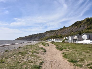 A coastal path beside pebble beach and mobile homes near cliffs at Sea Spray in Lyme Regis