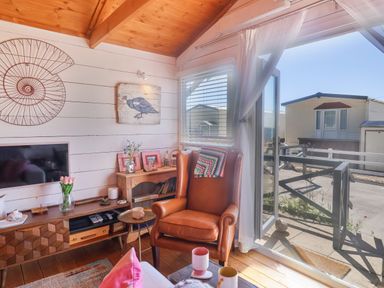 A living room with a leather armchair near a window and wooden furniture at Sea Spray in Lyme Regis