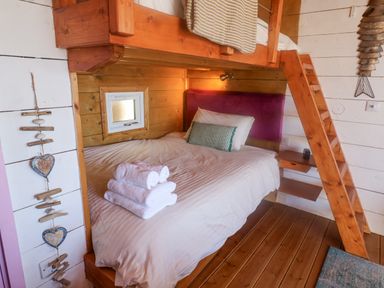 A small bedroom with a double bed below a wooden bunk bed and ladder at Sea Spray in Lyme Regis