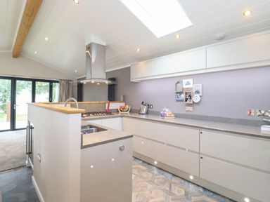A kitchen with cooking area and sink under skylight at Loubi's Lakeside Lodge M1 Fallbarrow Park near Bowness-On-Windermere