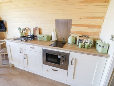 A kitchen counter with sink microwave stovetop kettle toaster and storage containers at Ailsa Craig in Hillhampton Great Witley