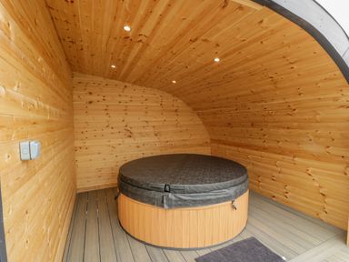 A wooden room with a covered round hot tub and a small floor mat at Laird Lodge 2 in Lochmaben
