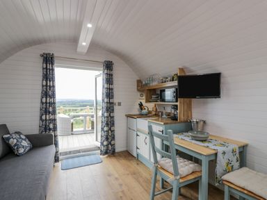 A small kitchen and seating area with a table and chairs beside an open door leading to a balcony at Laird Lodge 2 in Lochmaben