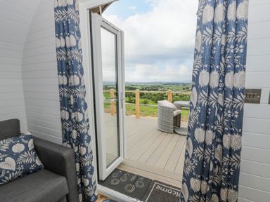 A door open to a deck with patio furniture and a view of fields at Laird Lodge 2 in Lochmaben