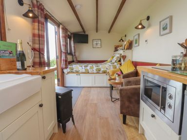 A living room with a bed and kitchen area at The Herdsman Luxury Shepherds Hut Barnoldswick