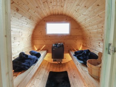 A sauna with wooden benches and a heating unit at The Herdsman Luxury Shepherds Hut in Barnoldswick