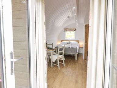 A bedroom with a double bed a small table with two chairs and wooden flooring at Laird Lodge 4 Lochmaben