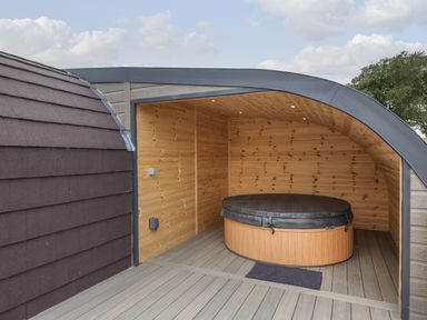 A covered wooden hot tub on a wooden deck at Laird Lodge 4 in Lochmaben