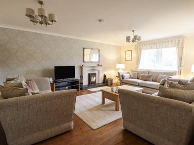 A living room with beige sofas a coffee table a fireplace and a television at Tan Yr Allt in Dolanog near Meifod Powys