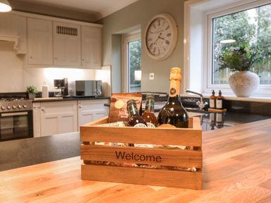 A kitchen with a wooden crate containing bottles and snacks on a countertop at Tan Yr Allt in Dolanog near Meifod Powys