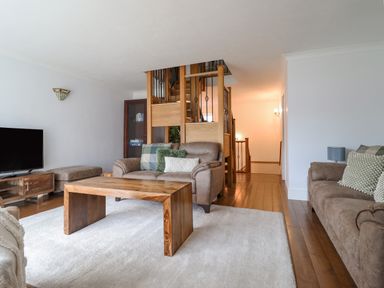 A living room with sofas a wooden coffee table a TV on a stand and a staircase with wooden and metal railings at Tan Yr Allt in Dolanog near Meifod Powys