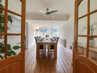 A dining room with a long wooden table set with plates and glasses and chairs around it at Tan Yr Allt in Dolanog near Meifod Powys