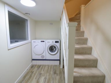A laundry area with a washing machine and dryer next to a carpeted staircase at Tan Yr Allt in Dolanog near Meifod Powys