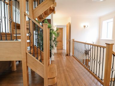 A wooden staircase with black metal balusters and wooden floor in a hallway at Tan Yr Allt in Dolanog near Meifod Powys