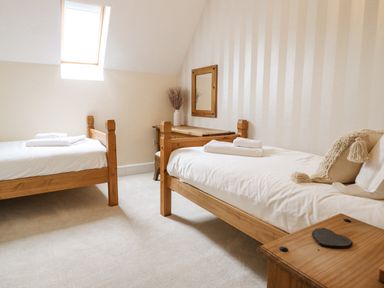 A bedroom with two wooden single beds a wooden desk with a mirror and a small wooden side table at Tan Yr Allt in Dolanog near Meifod Powys