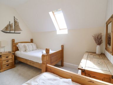 A bedroom with two wooden beds a wooden nightstand a dresser with a vase and a skylight at Tan Yr Allt in Dolanog near Meifod Powys