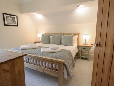 A bedroom with a wooden bed and bedside tables with lamps at Tan Yr Allt in Dolanog near Meifod Powys