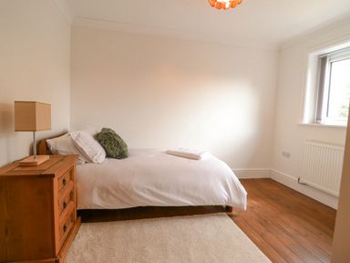 A bedroom with a single bed a wooden bedside table with a lamp and a window at Tan Yr Allt in Dolanog near Meifod Powys