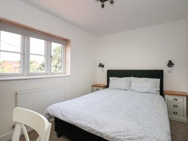 A bedroom with a double bed bedside tables window and a chair at Jolly Sailors Retreat - Wells next the Sea in Wells-Next-The-Sea