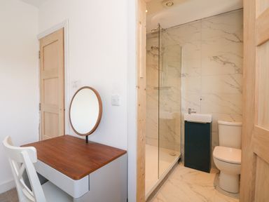 A small desk with a round mirror next to a bathroom with a shower toilet and sink at Jolly Sailors Retreat - Wells next the Sea in Wells-Next-The-Sea