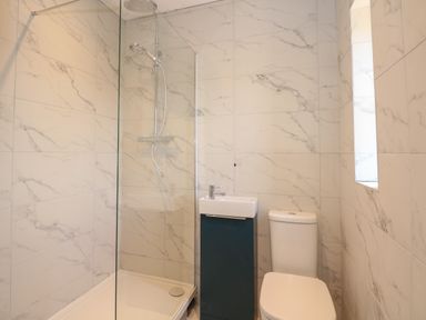 A small bathroom with a shower, sink, and toilet at Jolly Sailors Retreat - Wells next the Sea in Wells-Next-The-Sea