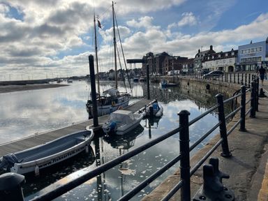 A harbor with boats docked along a quay and buildings lining the waterfront at Jolly Sailors Retreat - Wells next the Sea in Wells-Next-The-Sea