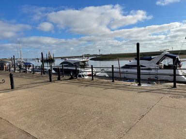 A harbor with boats docked next to a concrete walkway and black railings at Jolly Sailors Retreat - Wells next the Sea in Wells-Next-The-Sea