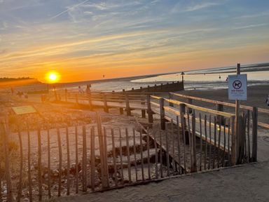 A wooden boardwalk and fence at the beach during sunset at Jolly Sailors Retreat - Wells next the Sea