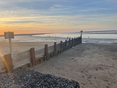 A beach with wooden groynes and a warning sign near the shoreline at Jolly Sailors Retreat - Wells next the Sea in Wells-Next-The-Sea
